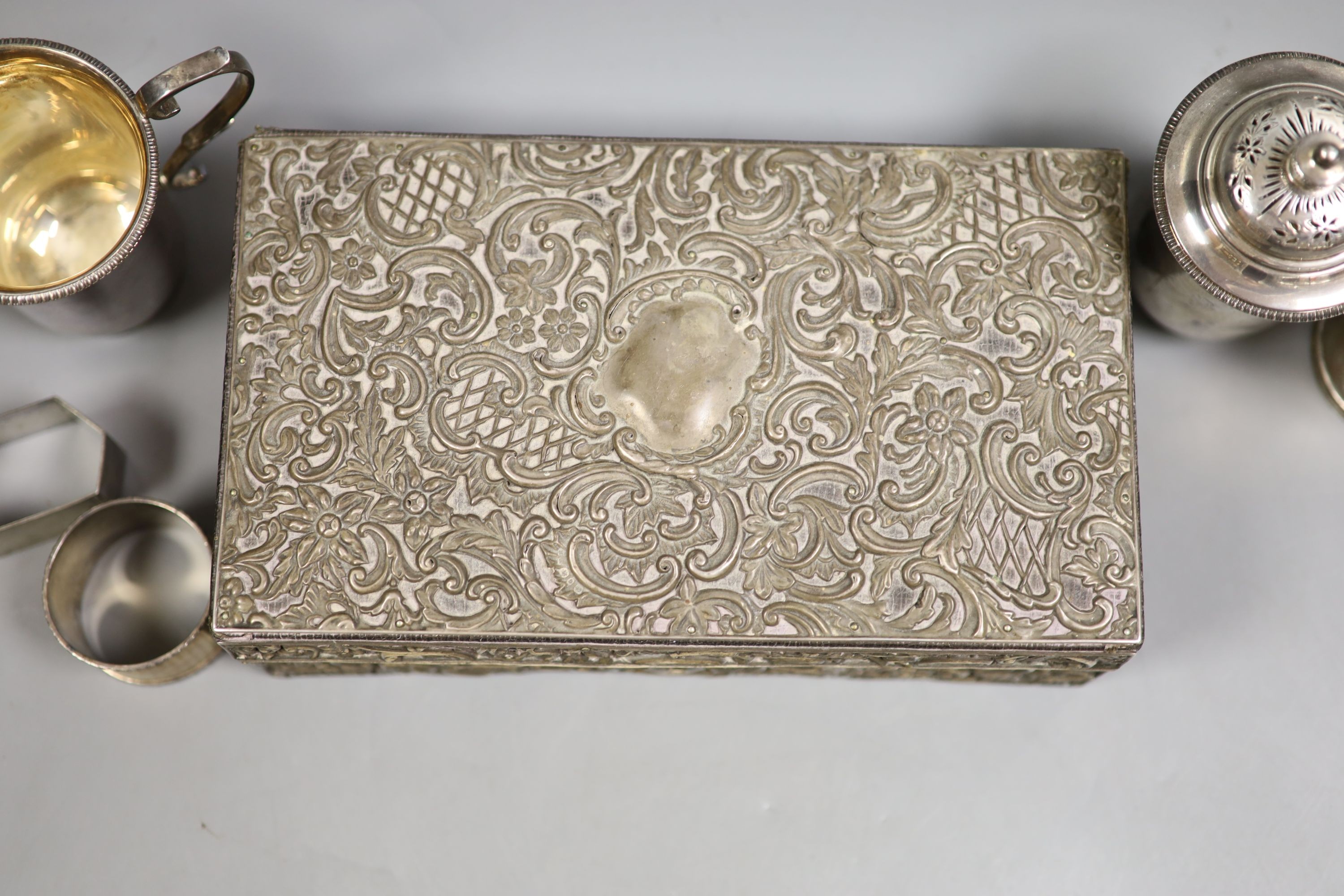 A late Victorian silver mounted leather rectangular jewellery casket, 23.2cm, a silver snuff box, the lid embossed with a wild fowling scene, a George V silver cream jug and pepper, two silver napkin rings and a Victoria